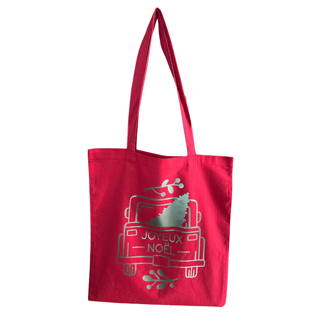 Tote bag rouge avec une image ecrit Joyeux Noël posé sur un fond blanc.