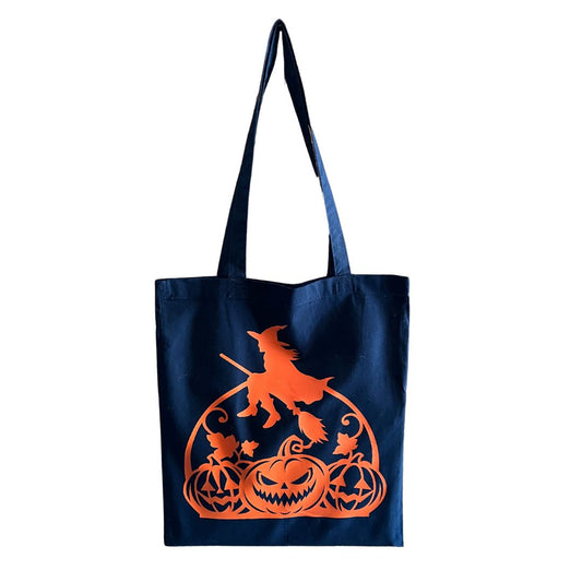 Tote bagnoir avec une image de sorcière et citrouille orange posé sur un fond blanc.