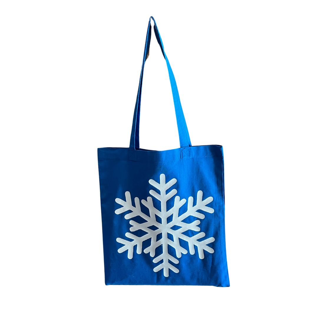 Tote bag bleu avec un flocon blanc, posé sur un fond blanc.