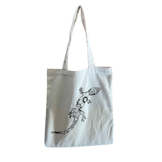 Tote bag blanc avec un lézard noire posé sur un fond blanc.