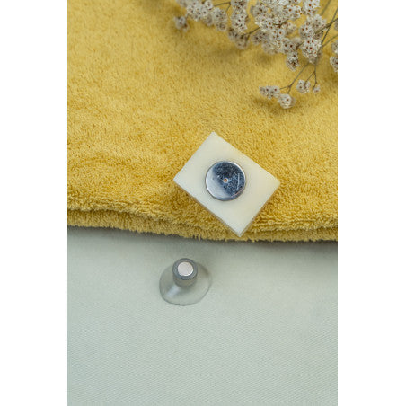 Porte savon aimanté avec un savon sur une serviette jaune.